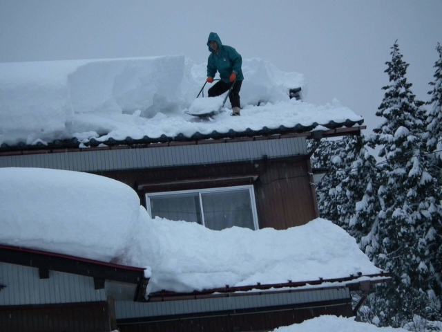 屋根の雪かきをする人物